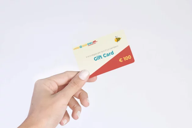 Mano che stringe la gift card di Made4YourBaby del valore di € 100, per fare un regalo a bambini e i loro genitori