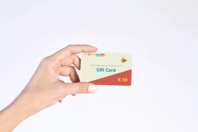 Mano che stringe la gift card di Made4YourBaby del valore di € 50, per fare un regalo a bambini e i loro genitori