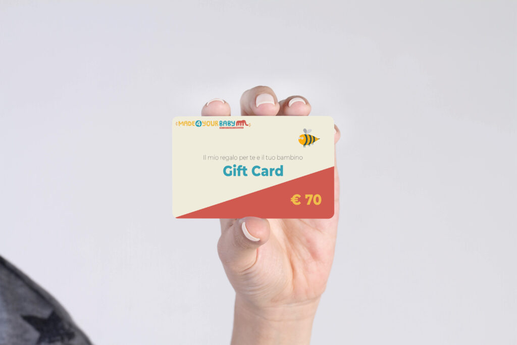 Mano che stringe la gift card di Made4YourBaby del valore di € 25, per fare un regalo a bambini e i loro genitori