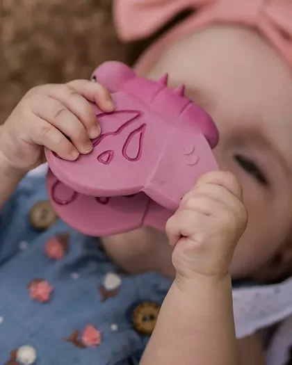 Bambina che gioca con gioco per neonati in gomma naturale a forma di farfalla rosa