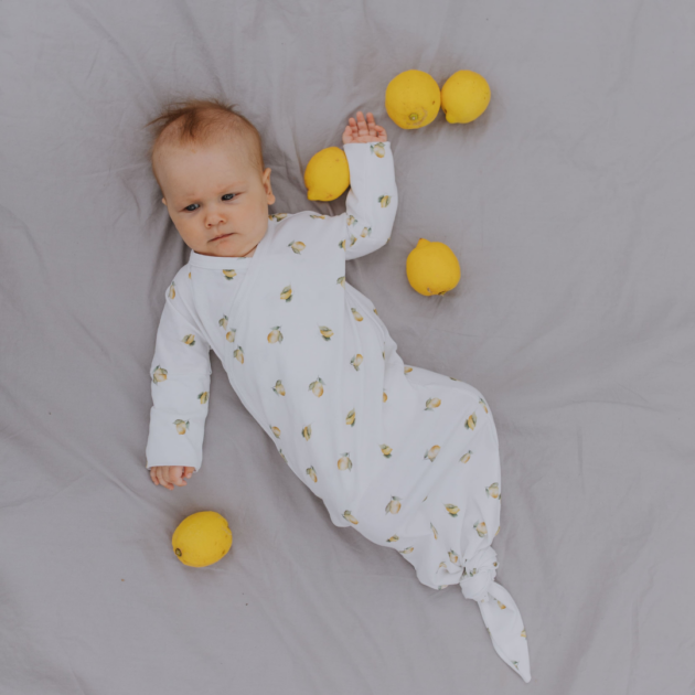 bambino su lenzuola con tutina a tema limoni