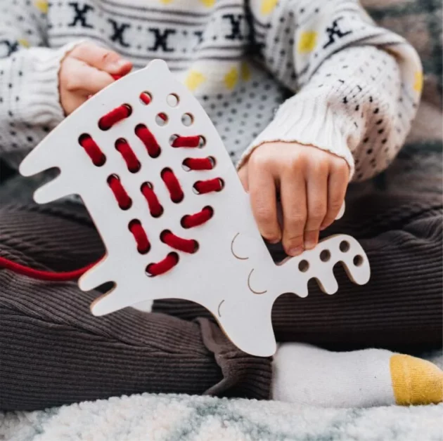 mani di bambino che gioca con Giocattolo educativo Montessori ad intreccio in legno a forma di renna con lacci rossi