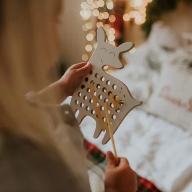 mani di bambina che gioca con giocattolo educativo Montessori ad intreccio in legno a forma di cerbiatta con lacci arancioni