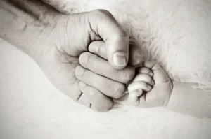 mano di un adulto e mano di un neonato
